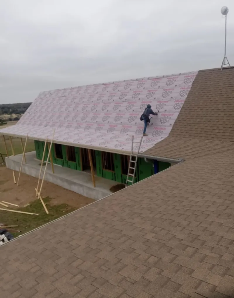 Worker preparing underlayment for a metal roof installation in Blair